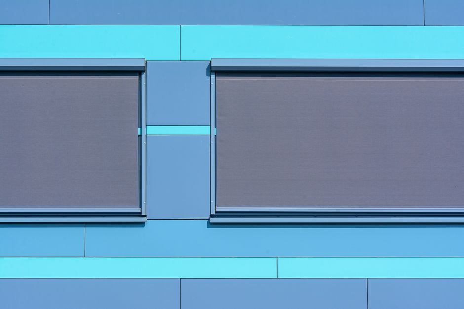 Imagem de um edifício com fachadas modernas e detalhes em diferentes tons de azul, destacando sua arquitetura contemporânea.