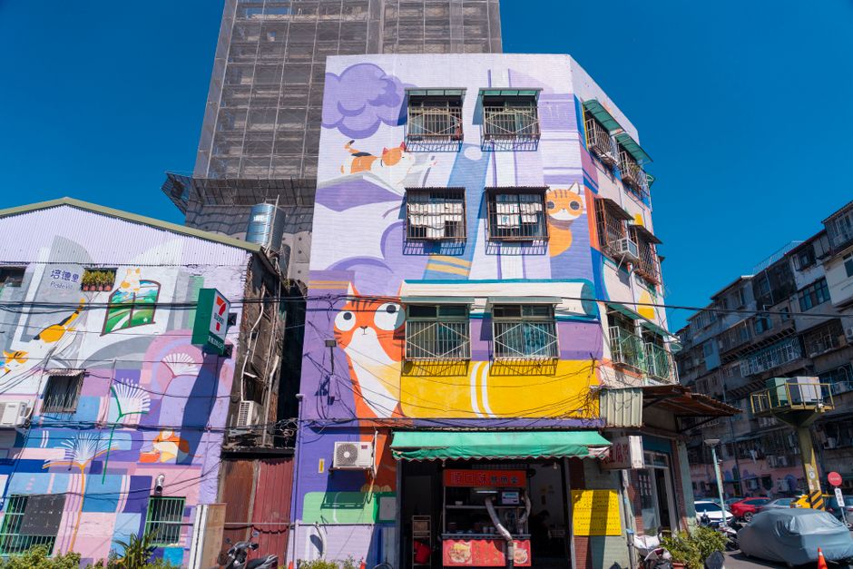 Mural artístico colorido de gatos em um edifício urbano, destacando a criatividade e o street art na cidade.