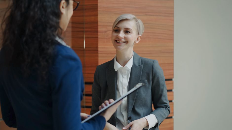 Mulher sorridente em entrevista de emprego ou reunião de negócios em ambiente corporativo.