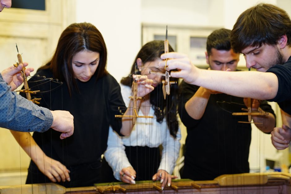 Grupo de pessoas participando de uma atividade educativa prática envolvendo construção de um sistema de marionetes de madeira.