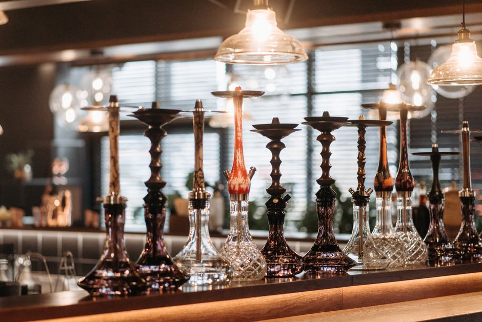 Imagem de uma decoração elegante com vários cachimbos de narguilé em um ambiente interno aconchegante com iluminação quente e janelas com persianas.