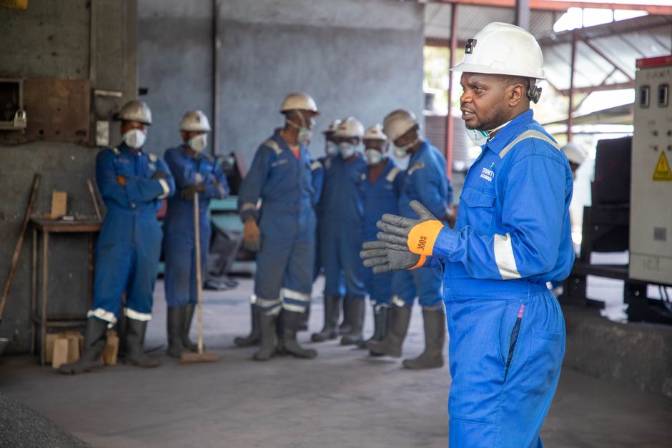 Instrutor de segurança prestando treinamento de procedimentos para um grupo de trabalhadores em uma usina industrial.