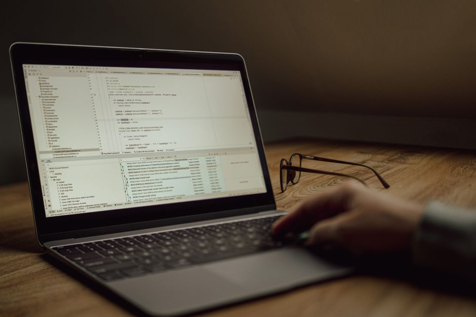 Pessoa trabalhando com programação ou desenvolvimento de software em um laptop com foco em código fonte, ideal para artigos sobre tecnologia ou inovação.