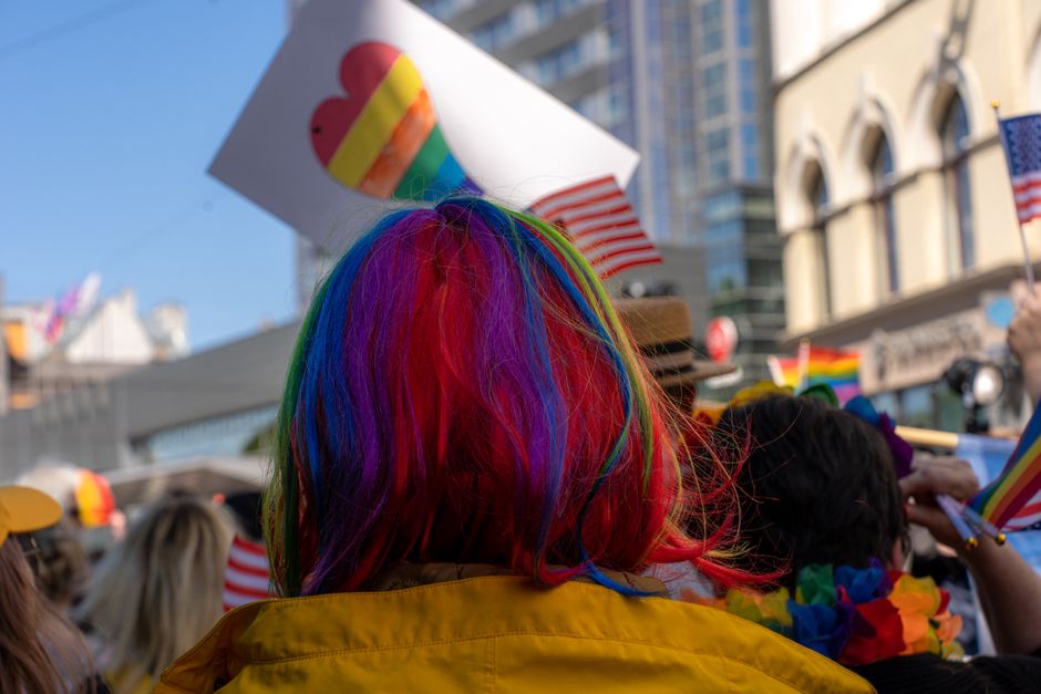 Pessoas participando de uma manifestação ou parada do orgulho LGBTQ+ ao ar livre, simbolizando diversidade e inclusão.