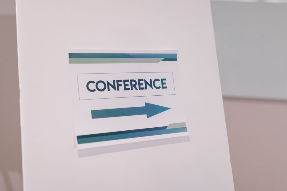 Placaindicando a direção para uma conferência, simbolizando eventos corporativos e networking profissional.