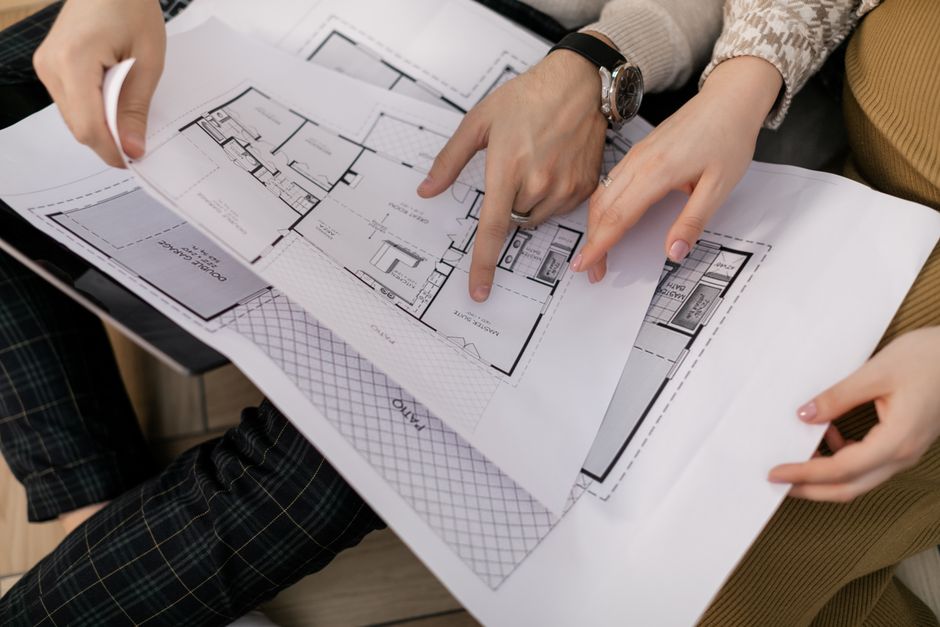 Duas pessoas analisando e discutindo um projeto de arquitetura ou planta de uma construção.