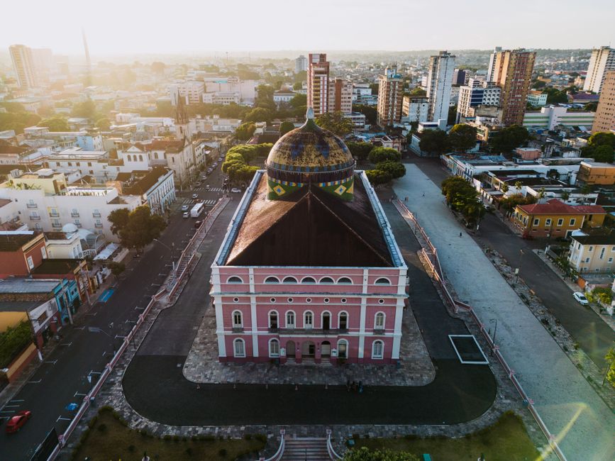 Imagem de uma cidade vista do alto, destacando um prédio histórico de cor rosa com uma cúpula decorada, simbolizando a combinação entre história e urbanismo moderno.