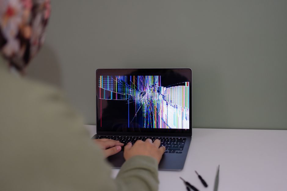 Pessoa usando um laptop com uma tela que exibe uma representação visual de dados ou código, sugerindo tecnologia ou análise digital.