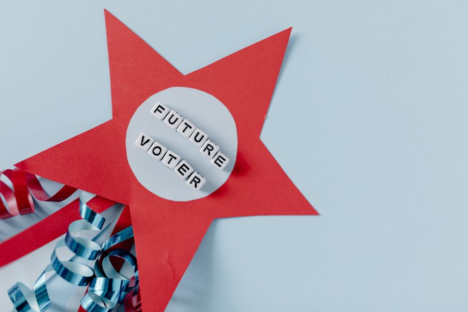 Imagem de uma estrela de papel vermelha com a mensagem 'FUTURE VOTER' em letras de quadrados, simbolizando a importância do participação cívica e do direito de voto no futuro.