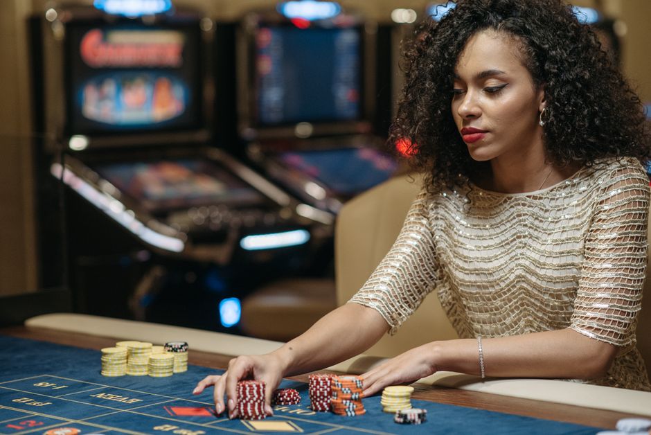 Mulher concentrada em jogo de pôquer em cassino, com fichas empilhadas na mesa, demonstrando foco e estratégia