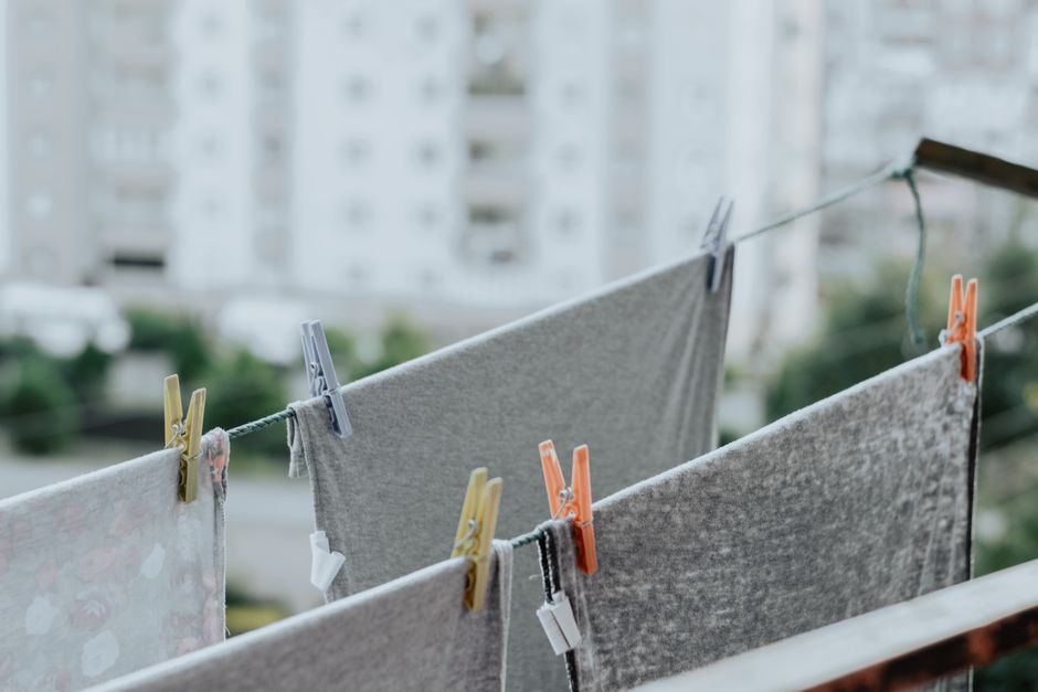 Roupas de lavado penduradas em uma corda no exterior de um prédio residencial, com foco na rotina de cuidados domésticos e organização do dia a dia.
