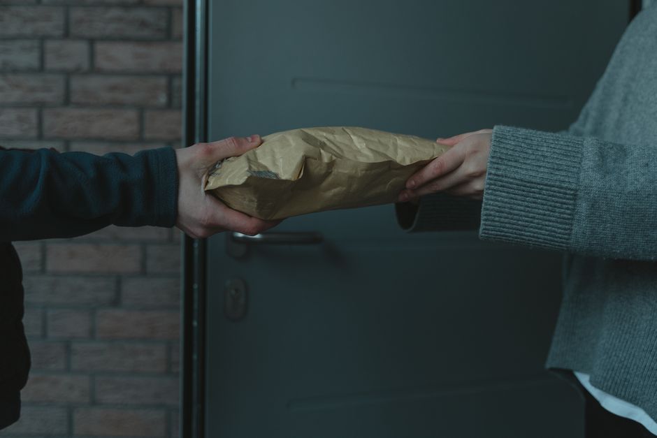 Pessoa entregando um pacote, simbolizando distribuição ou entrega de produtos em um ambiente urbano.
