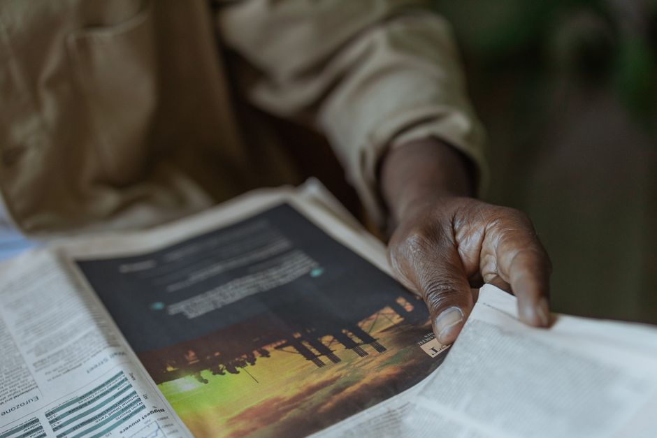 Pessoa lendo um jornal ao ar livre, destacando o tema de informação, notícias ou atualidades.