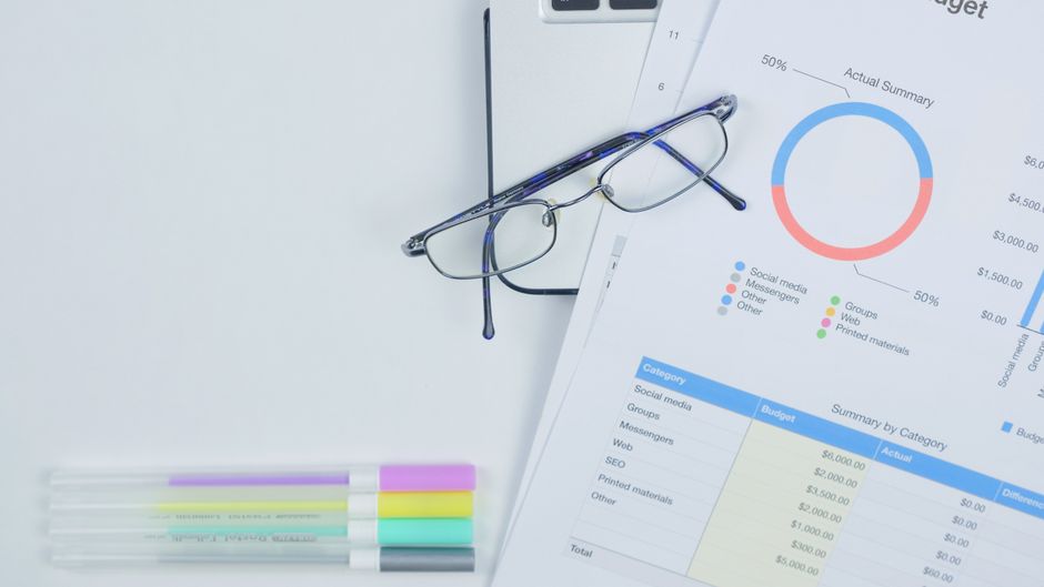 Ambiente de trabalho com foco em análise financeira e planejamento estratégico, incluindo gráficos, documentos e material de escritório.