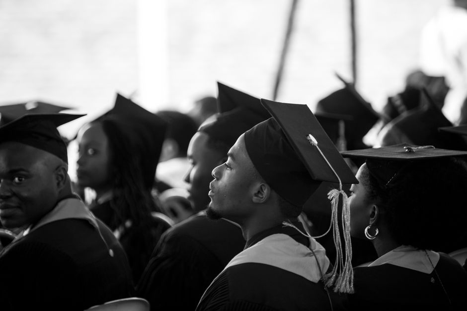 Estudantes de graduação assistindo a uma cerimônia de formatura em sala de aula ou auditório, celebrando uma conquista acadêmica.