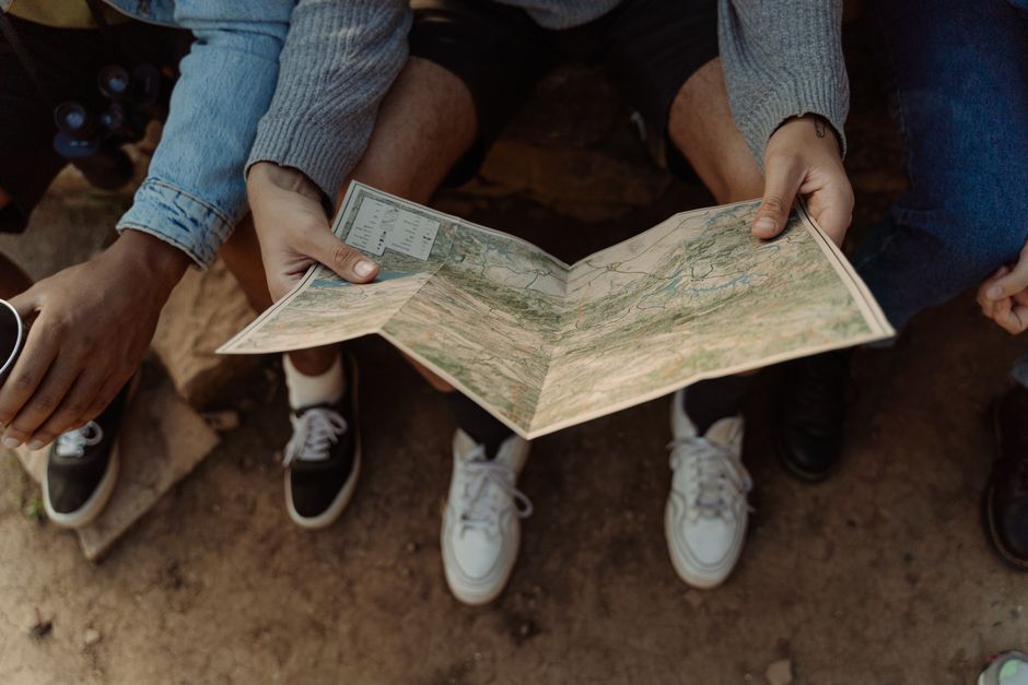 Grupo de pessoas explorando um mapa ao ar livre, simbolizando aventura e planejamento de viagens.