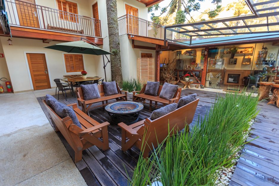 Área externa acolhedora com assentos de madeira e espaço para convivência ao ar livre, ideal para momentos de lazer e socialização em uma residência com jardim e espaço gourmet.