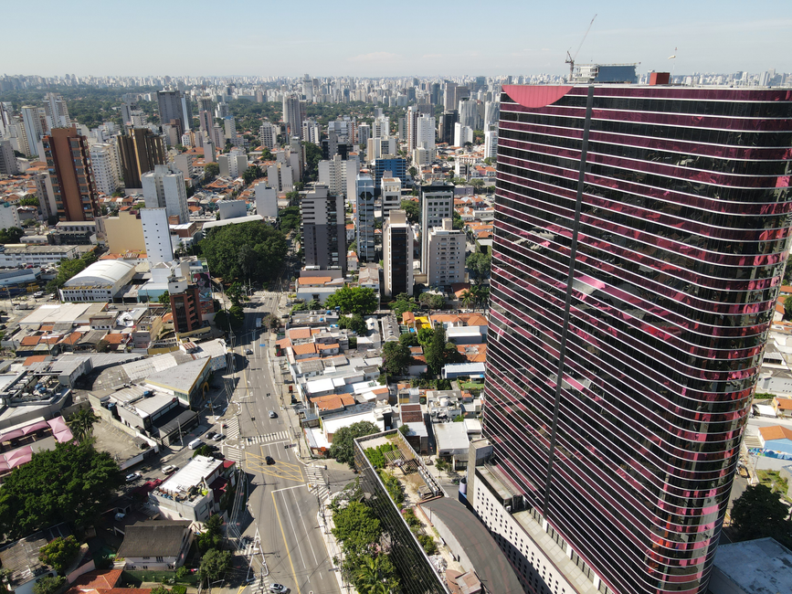 Imagem de uma vista aérea de uma cidade com edifícios altos e uma grande construção moderna, evidenciando o urbanismo e crescimento urbano.