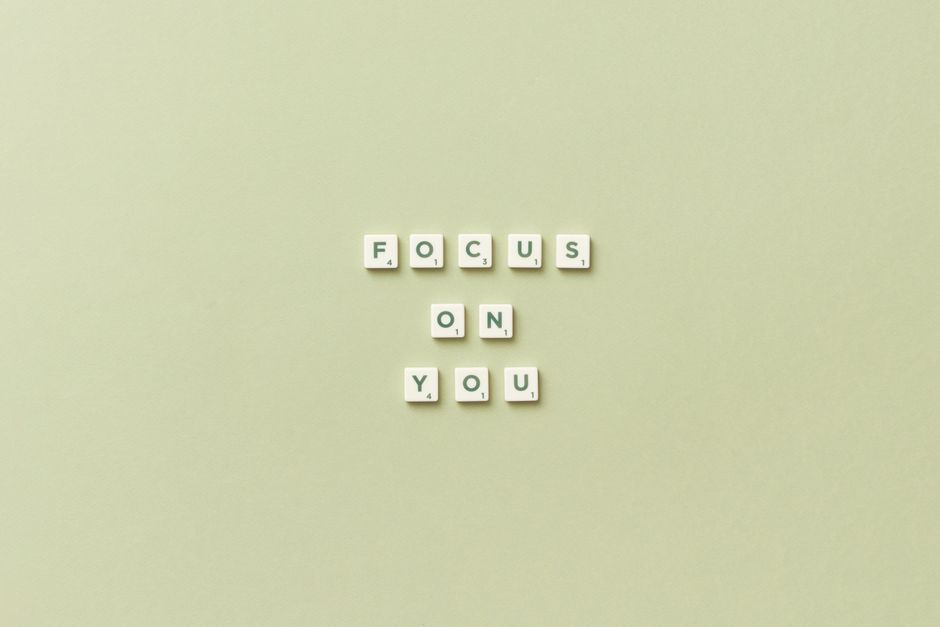 Conjunto de letras de xadrez formando a frase 'FOCUS ON YOU' em fundo de cor suave, transmitindo uma mensagem de atenção e cuidado pessoal.