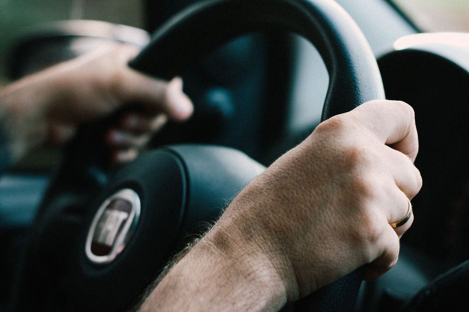 Pessoa dirigindo um carro, símbolo de transporte e mobilidade urbana.