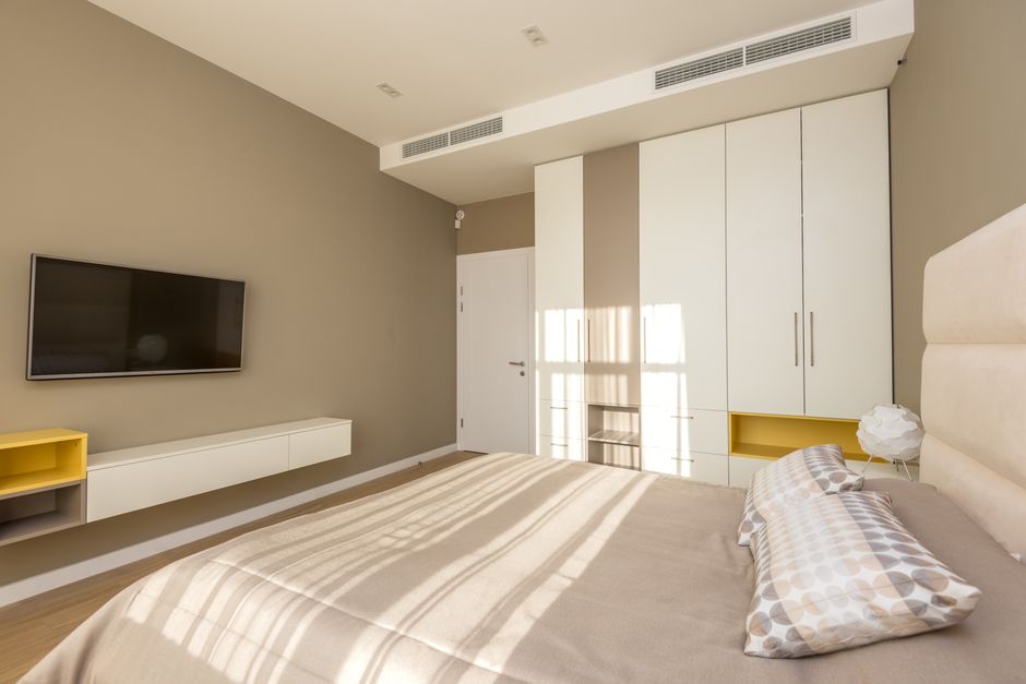 Quarto minimalista com decoração clean, iluminação natural e mobília moderna, ideal para ilustrar tendências de design de interiores e conforto residencial.