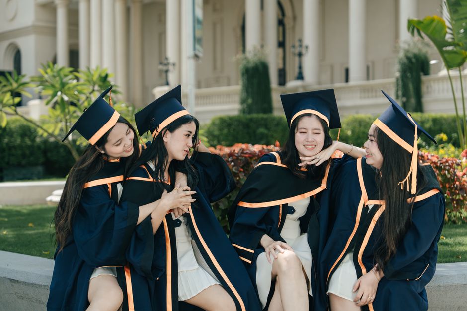 Grupo de estudantes recém-formados em cerimônia de graduação ao ar livre, celebrando a conquista com sorriso e amizade.