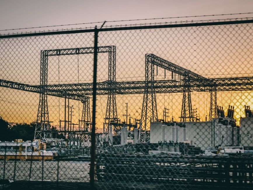 Imagem de uma subestação de energia ao pôr do sol, simbolizando infraestrutura elétrica e fornecimento de energia.