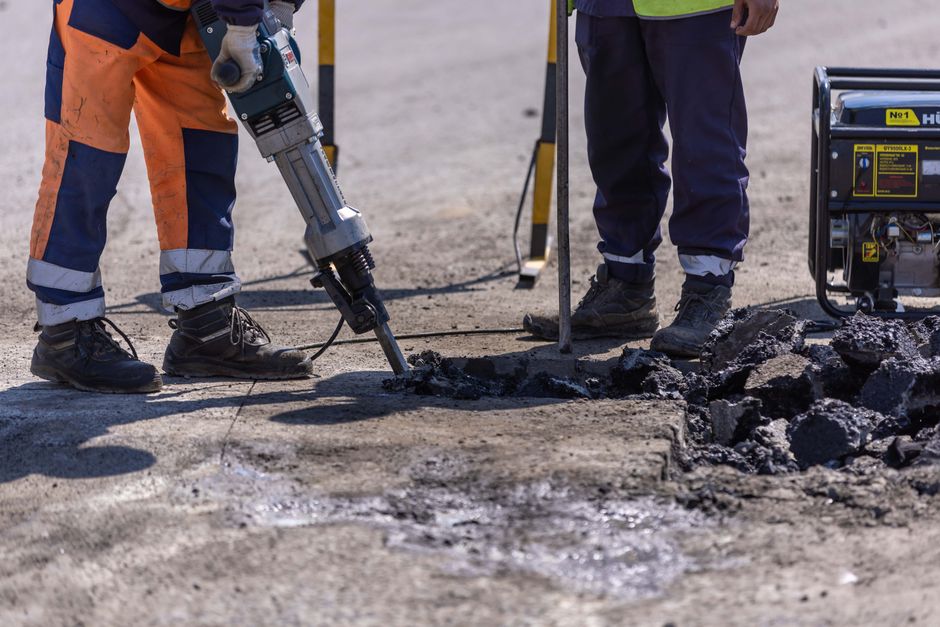 Homens trabalhando na construção de uma estrada ou pavimentação, com foco na execução de obra civil ao ar livre.