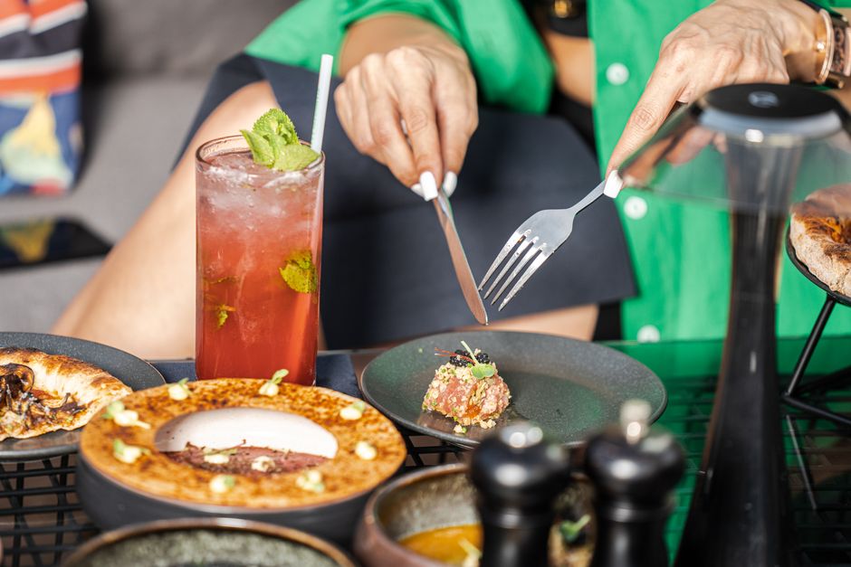 Pessoa degustando uma refeição sofisticada em restaurante, destacando a apreciação da gastronomia e momentos sociais.