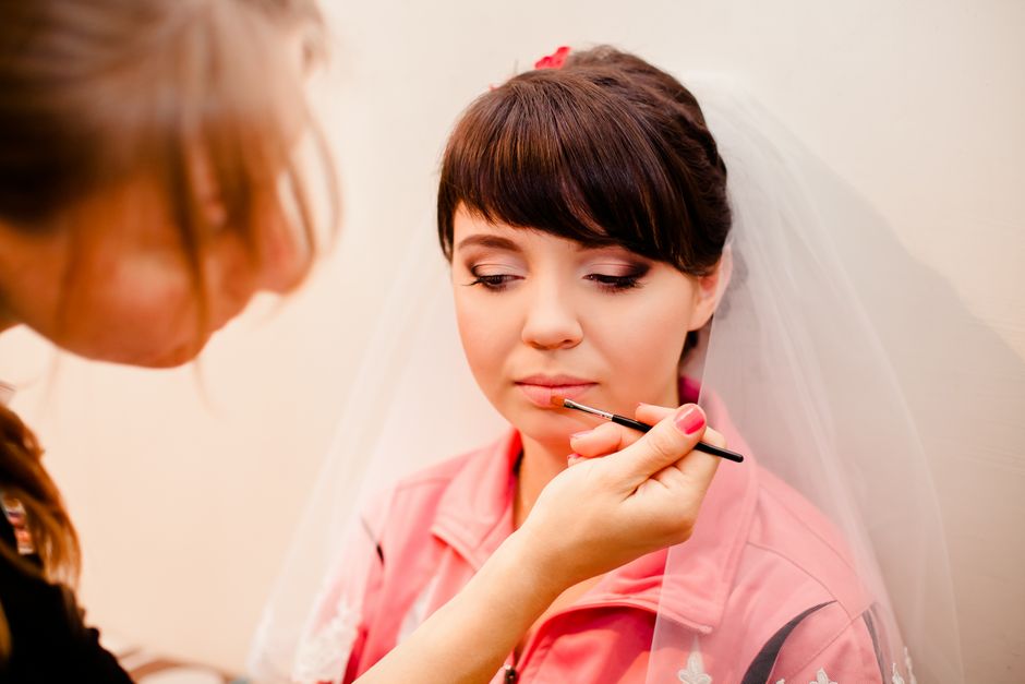 Mulher se preparando para o casamento, recebendo maquiagem e maquiagem de uma profissional, simbolizando beleza e preparação para um dia especial.