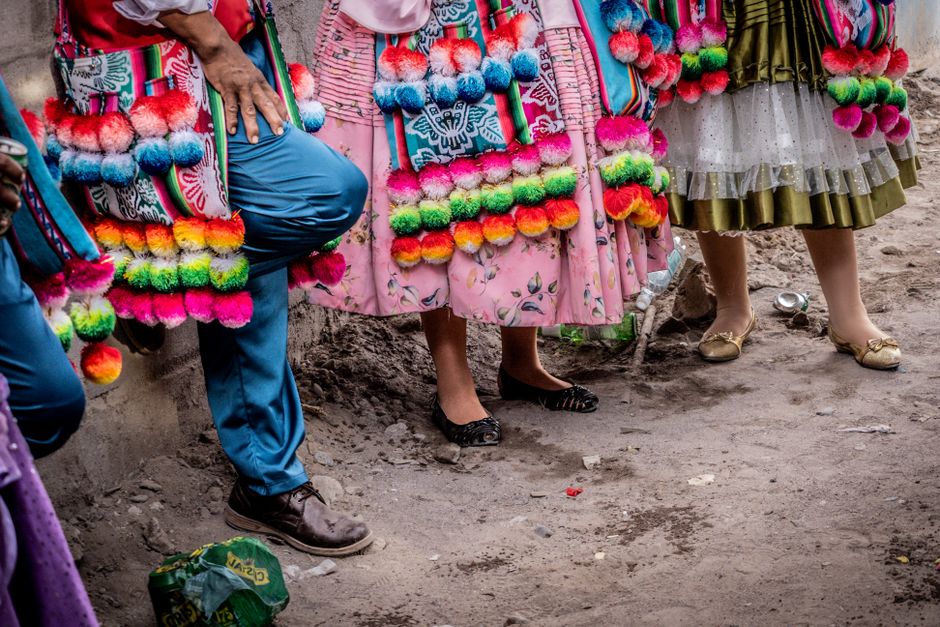 Grupo de pessoas vestindo roupas tradicionais decoradas com enfeites coloridos, refletindo uma celebração cultural ou festa folclórica.