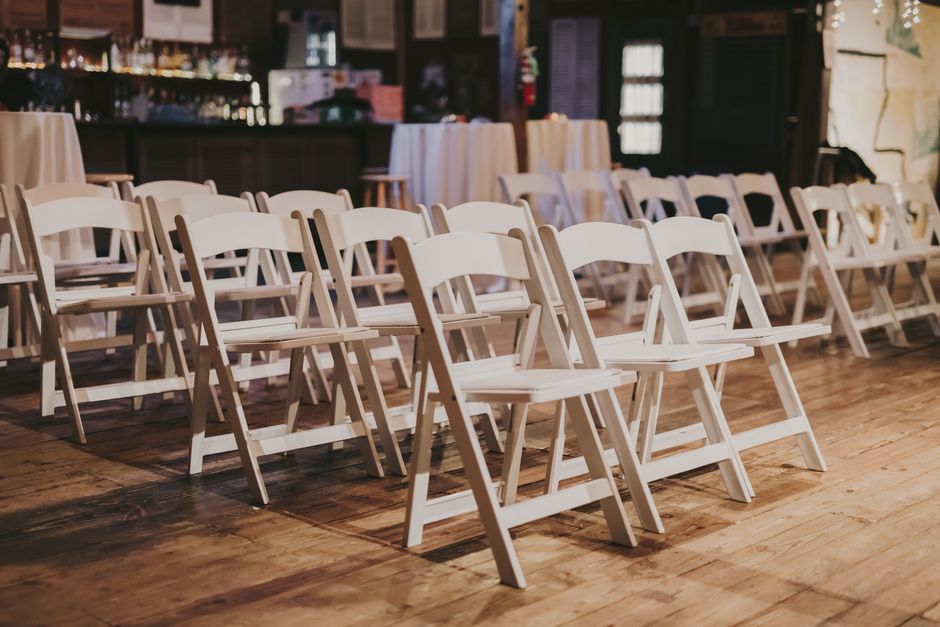 Fileira de cadeiras brancas prontas para um evento ou apresentação em um espaço versátil.