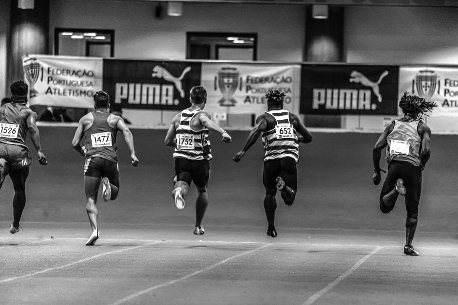 Atletas em uma corrida de pista indoor durante uma competição esportiva.