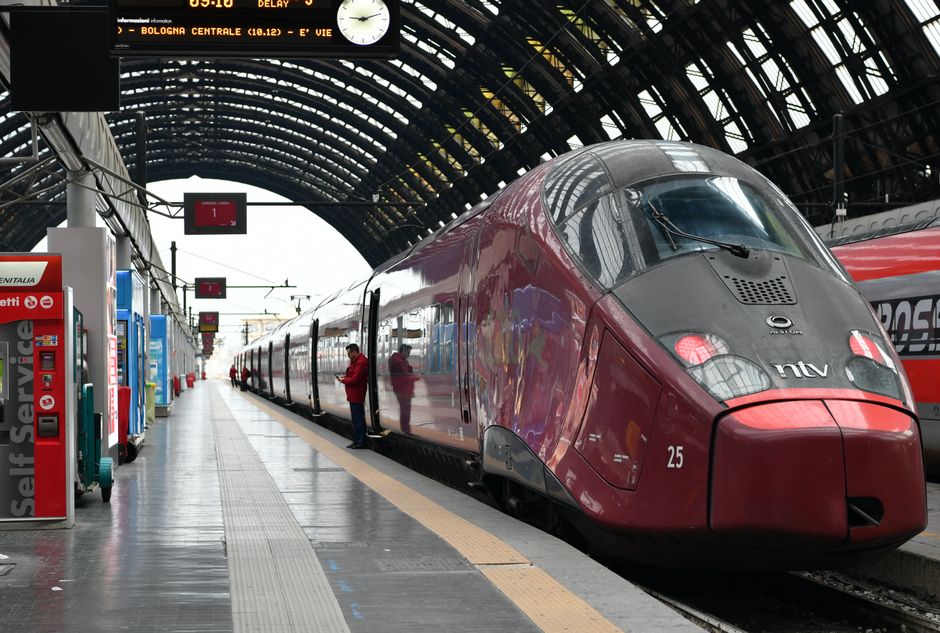 Trem de alta velocidade em uma estação de trem moderna com estrutura de vidro e ferro, pronto para embarque ou desembarque.
