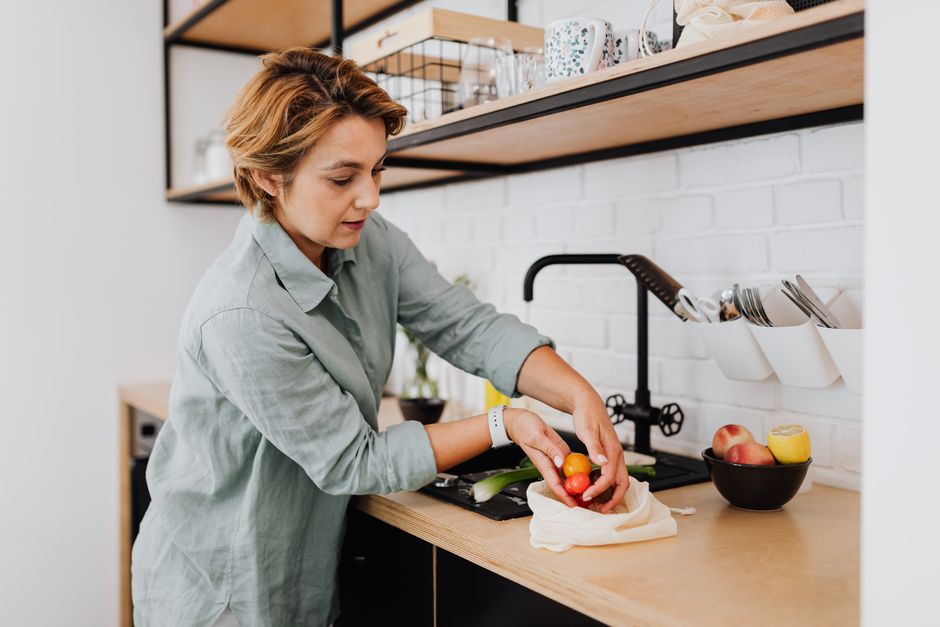 Mulher preparando uma refeição saudável na cozinha moderna, destacando o tema de alimentação e bem-estar.