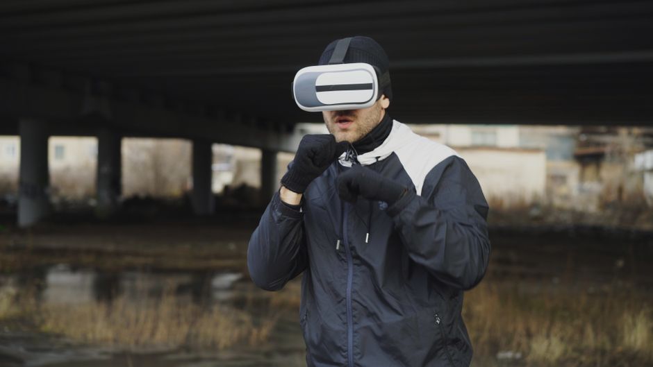 Homem utilizando fones de realidade virtual ao ar livre, explorando tecnologia imersiva.