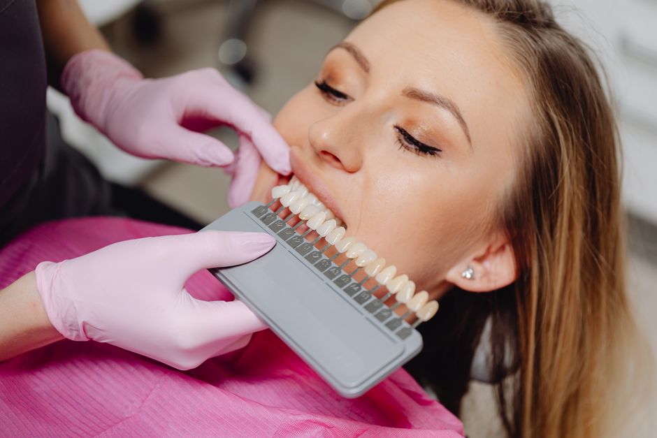 Mulher realizando avaliação de cor para estética odontológica em consultório, com foco na escolha da tonalidade dos dentes.