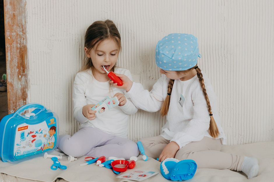 duas crianças brincando de médicos com brinquedos, simulando atendimento hospitalar em um ambiente doméstico