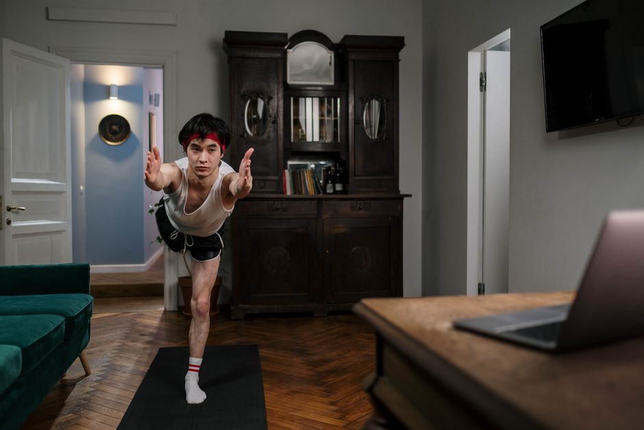 Homem praticando alongamento ou exercício físico em casa, demonstrando bem-estar e cuidado com a saúde.