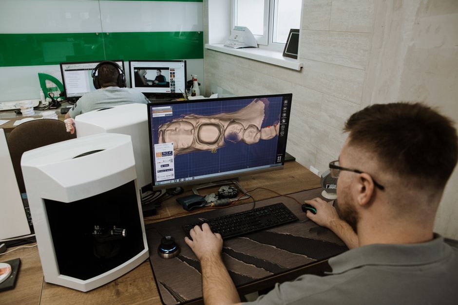 Pessoa trabalhando com modelagem 3D de um crânio humano em um ambiente de escritório de tecnologia.