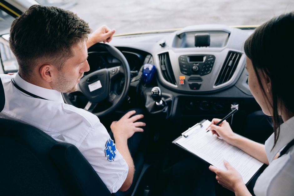 Profissional de saúde realizando avaliação com paciente dentro de um veículo, destacando a importância do transporte especializado em cuidados médicos.