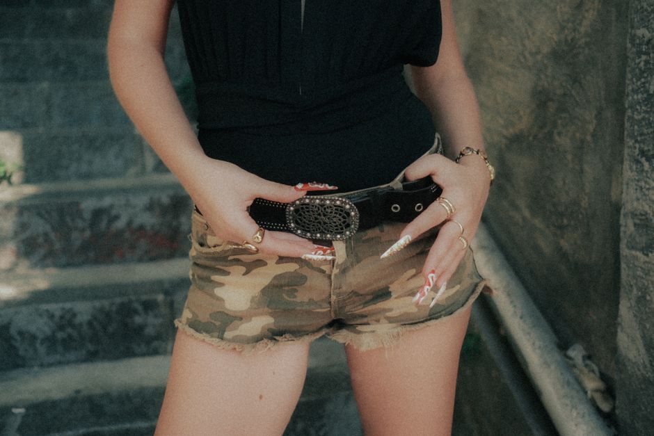 Jovem usando roupas casuais, com destaque para acessórios, em uma cena urbana ao ar livre.