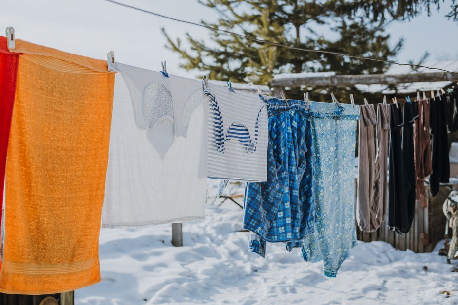 Roupa sendo secada ao ar livre em um ambiente com neve e árvores ao fundo.