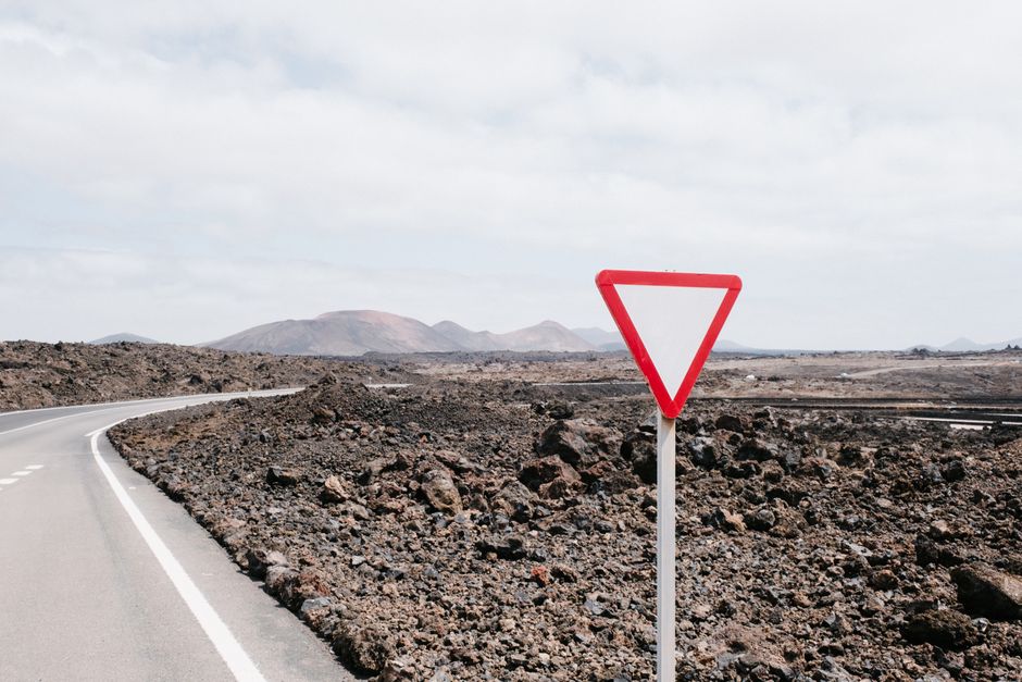Estrada em ambiente desértico com sinal de prioridade, simbolizando tomada de decisão e precauções na gestão de projetos ou negócios.