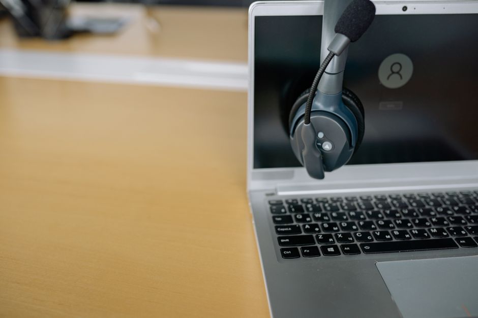 Imagem de laptop com um headset de comunicação, representando um ambiente de atendimento ou suporte ao cliente online.