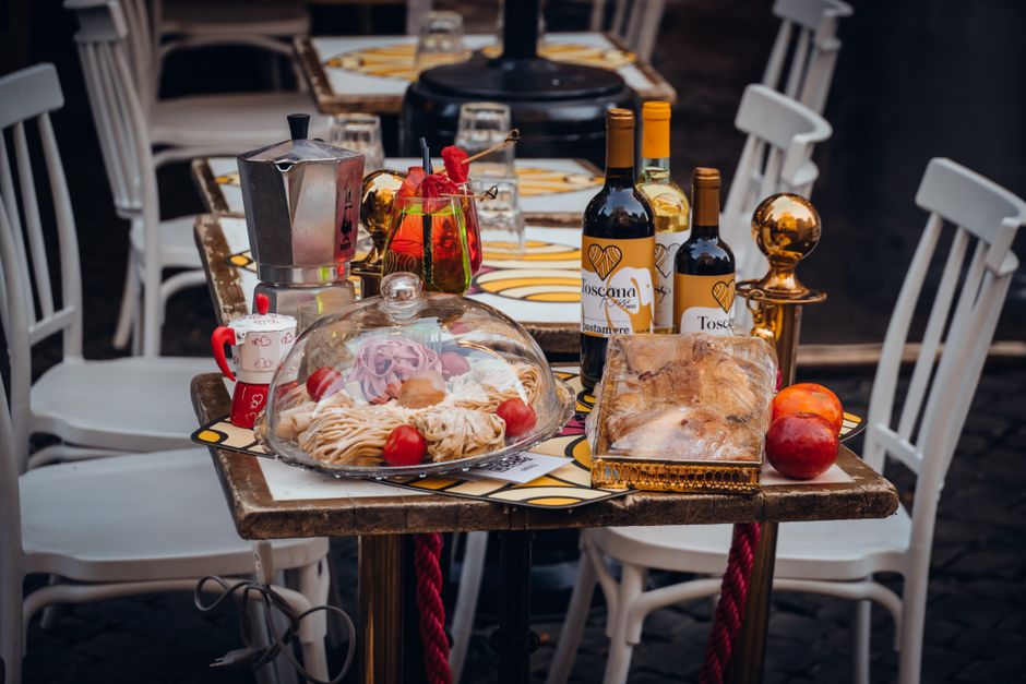 Mesa de celebração com comida, vinho e decoração, ideal para ocasiões especiais ao ar livre.