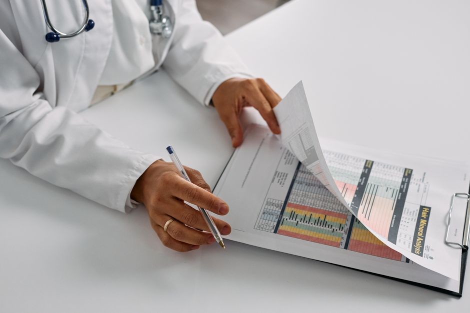 Profissional de saúde analisando relatórios médicos em uma mesa de consulta, destacando a importância da avaliação clínica e interpretação de exames.