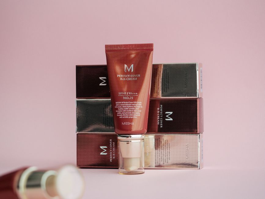 Imagem de produtos de maquiagem da linha de cosméticos Missha, com fundo rosa claro, destacando a embalagem e o design do produto.