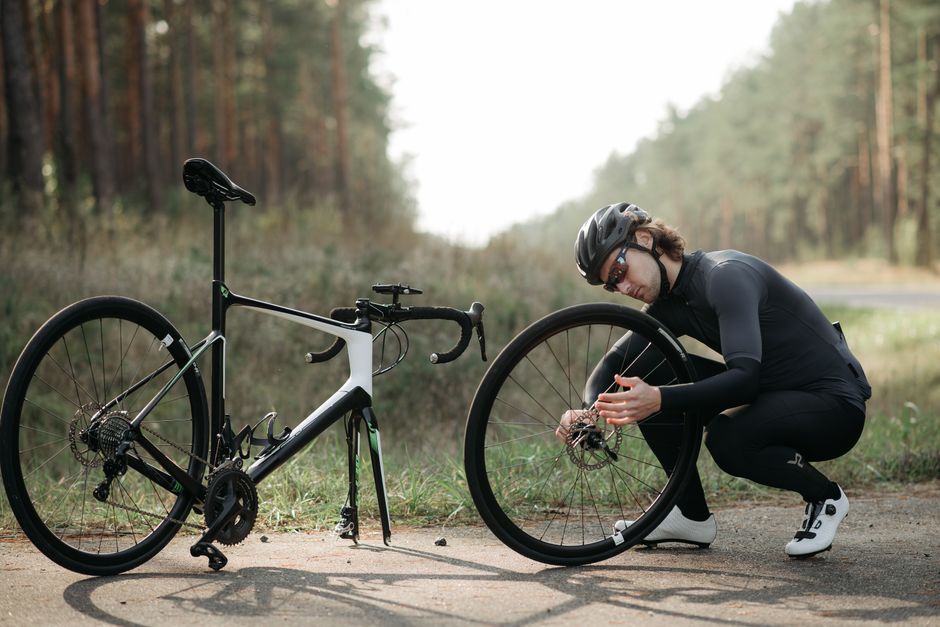 Pessoa realizando manutenção em uma bicicleta durante uma aventura ao ar livre em meio à natureza.