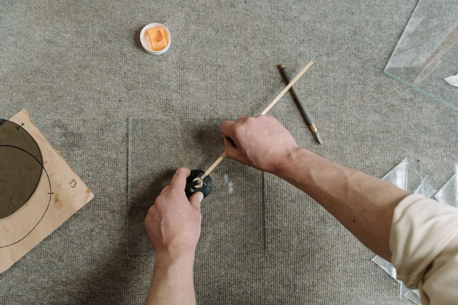 Pessoa ajustando um compasso em uma mesa, possivelmente em um ambiente de estudo ou oficina, com foco em medição e precisão.